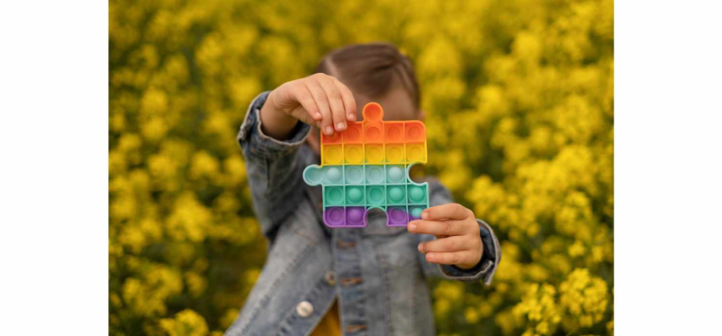 A child holds a popular toy popit rapeseed field.
