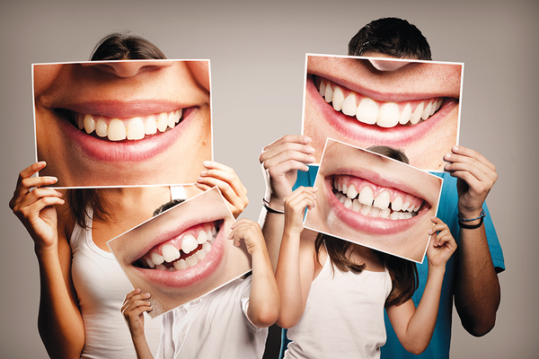 Family holding photos of smiling healthy teeth