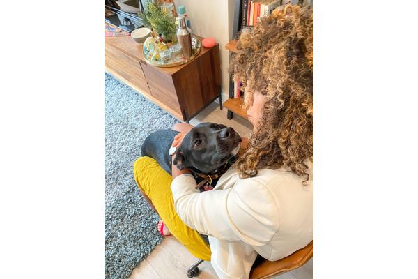 A woman and a dog face to face acting like they are kissing eachother