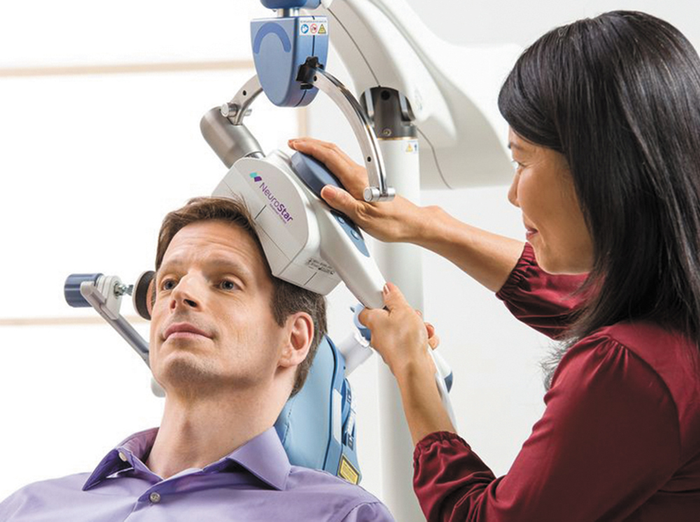 Patient receiving NeuroStar transcranial magnetic stimulation therapy from a health professional