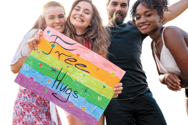 Group of people practicing small random acts of kindness holding sign saying free hugs