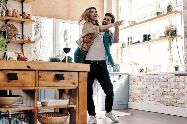 Couple laughing and dancing together in kitchen being playful