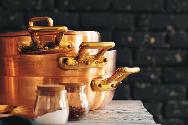 Stack of copper pots and pans sitting on counter next to spices