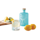 Cocktail in glass next to bottle of Gray Whale Gin lemons and sliced lime on cutting board