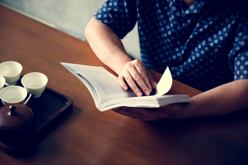 Man reading a book at a table.
