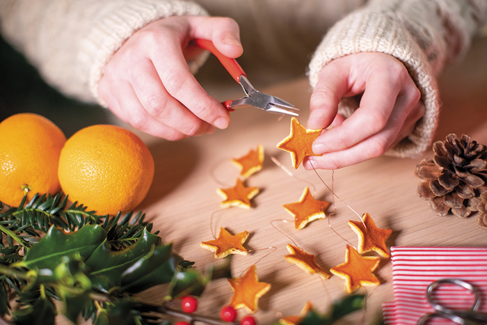 Hands using small scissors to make string of stars for homemade holiday decorations